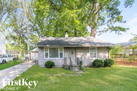 a small white house with a yard and trees
