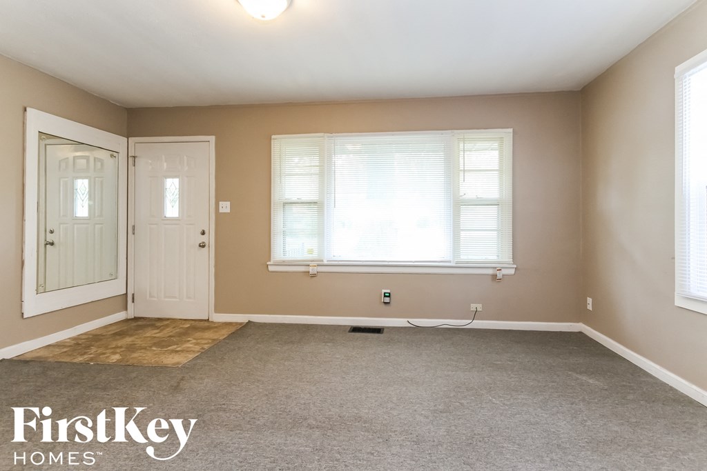 the living room of an empty house with a white door and window