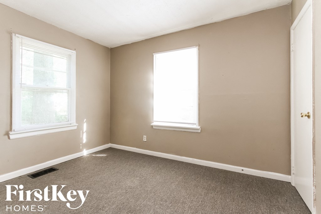 a bedroom with two windows and a carpeted floor