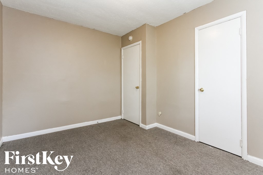 a bedroom with two doors and a carpeted floor