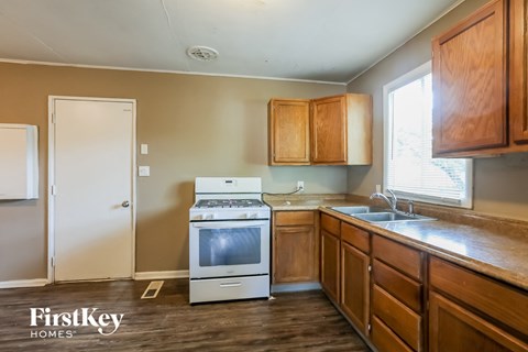 A kitchen with wooden cabinets and a white stove top oven.