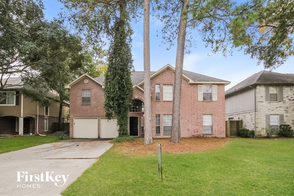 a brick house with two garage doors and a lawn