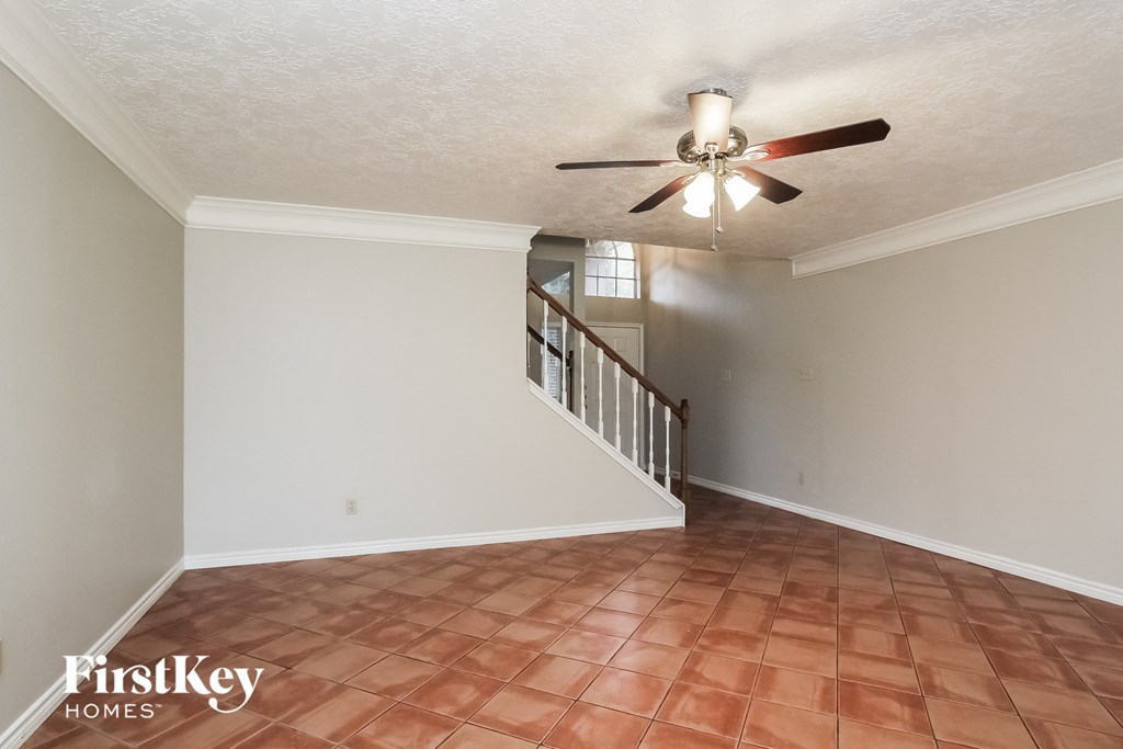 an empty living room with a ceiling fan and a staircase