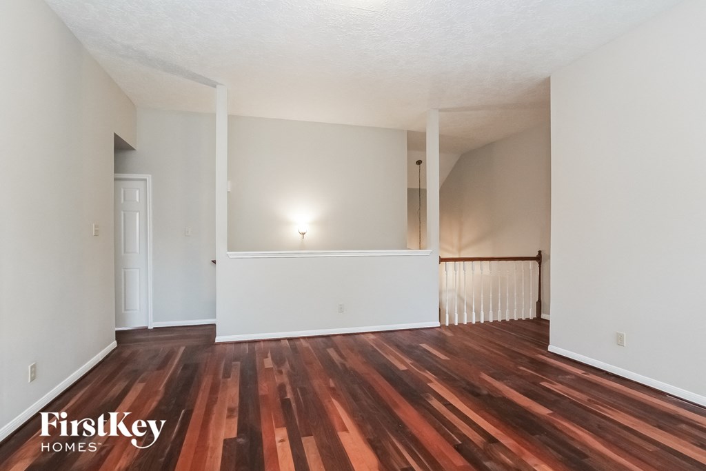an empty living room with wood flooring and white walls