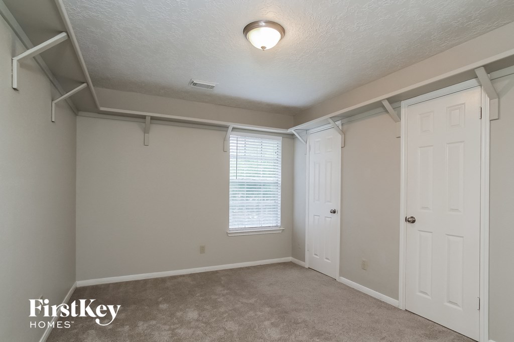 a bedroom with a closet and a white door and a window