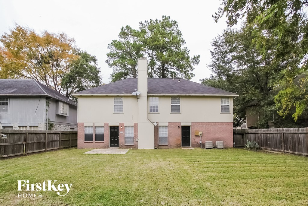 a white and brick house with a yard and a wooden fence