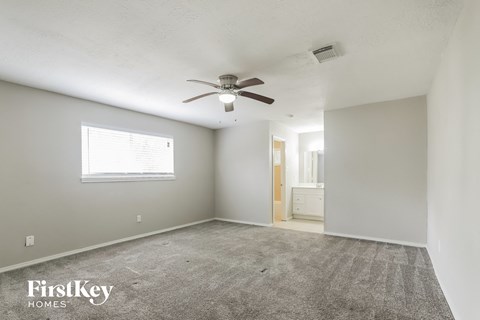 a living room with a ceiling fan and a carpet