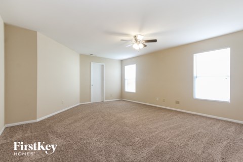a spacious living room with carpet and a ceiling fan