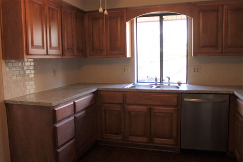A kitchen with wooden cabinets and a marble countertop.