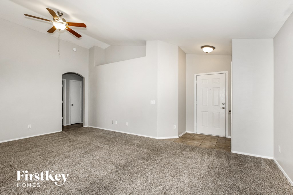 a living room with white walls and a ceiling fan