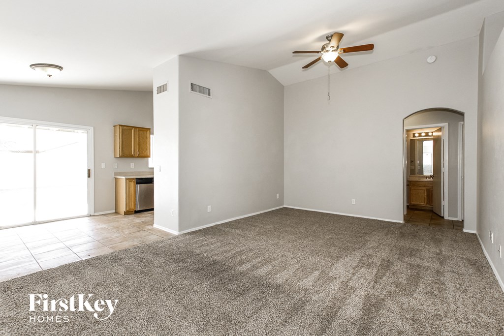 an empty living room with a ceiling fan