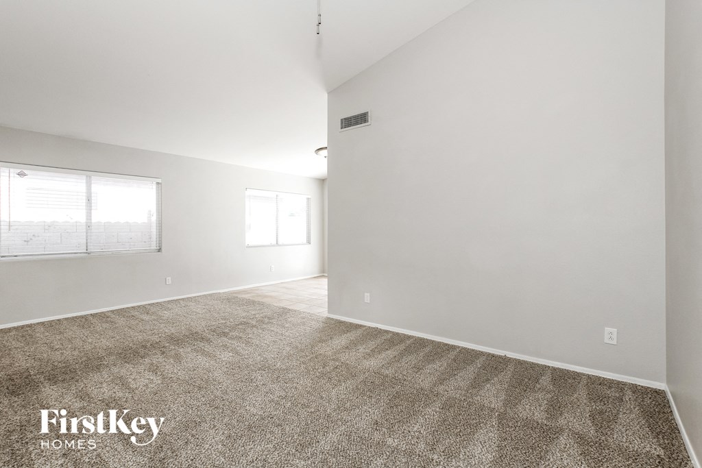 the living room and dining room with white walls and carpet