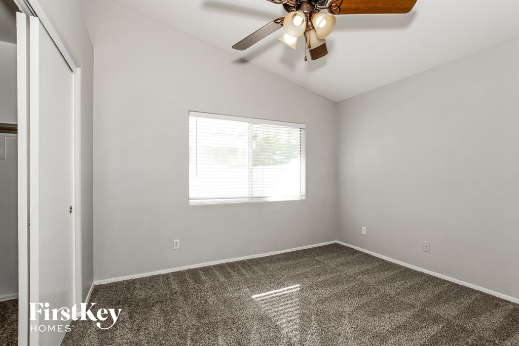 an empty room with a ceiling fan and a window