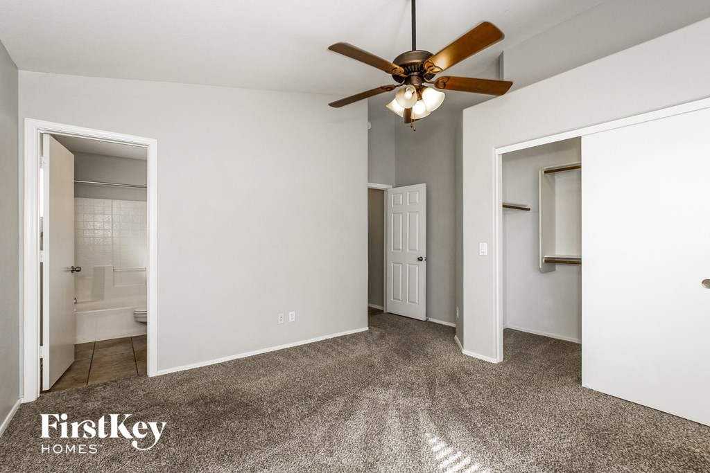 a bedroom with white walls and a ceiling fan