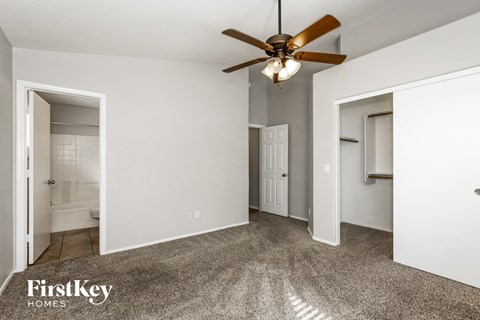 a bedroom with white walls and a ceiling fan