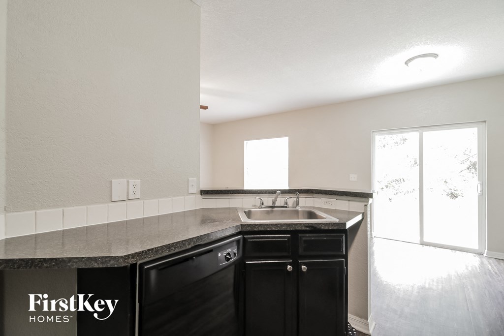 a kitchen with black cabinets and a sink and a window