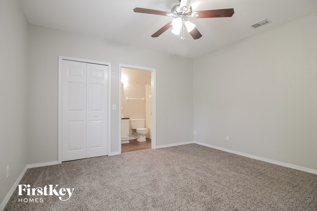 a bedroom with a ceiling fan and a door to a bathroom