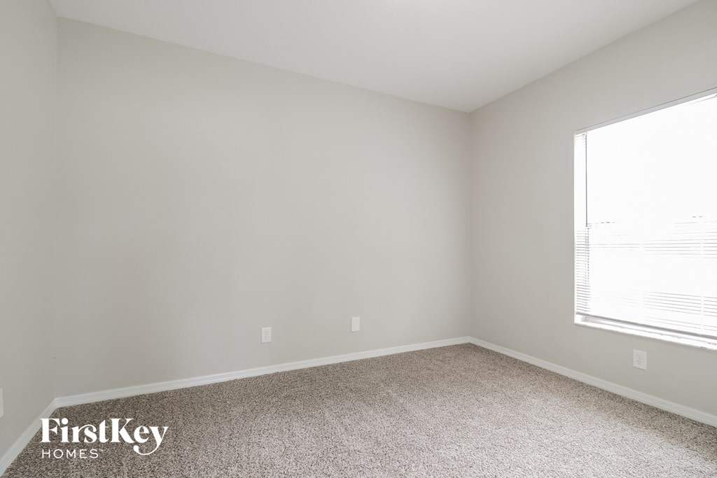 a bedroom with a window and a carpeted floor