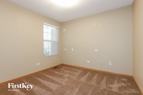 the living room of a new home with carpet and a window
