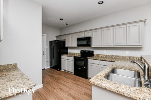a kitchen with white cabinets and black appliances