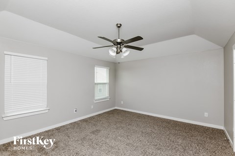 the spacious living room with ceiling fan and carpet