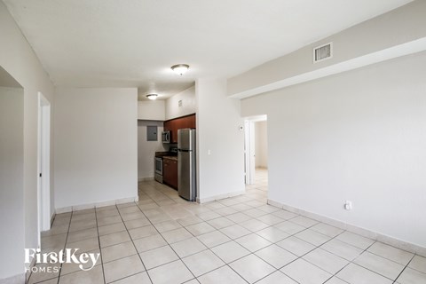 A spacious room with a kitchenette in the background.