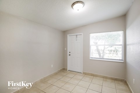 A room with a white door and a window with a view of trees.