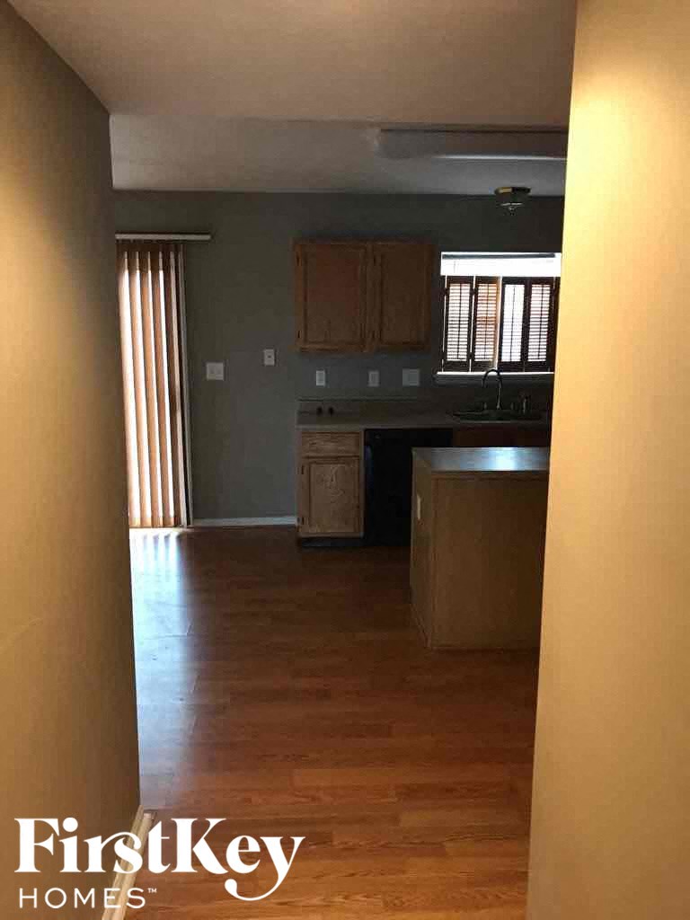 A kitchen with wooden floors and a window with blinds.