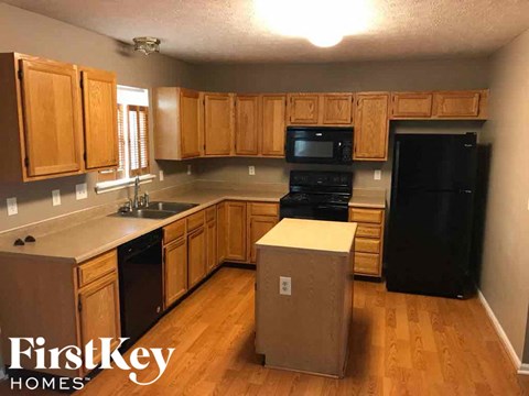 A kitchen with wooden cabinets and a black fridge.