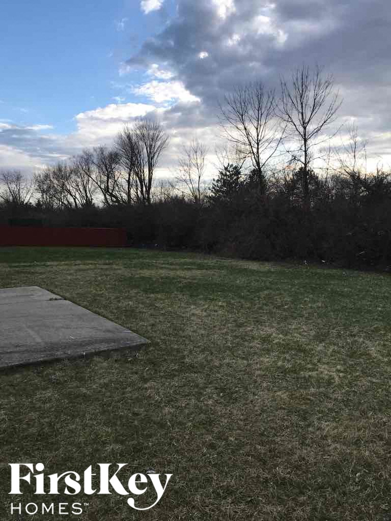 A grassy field with a wooden board and trees in the background.