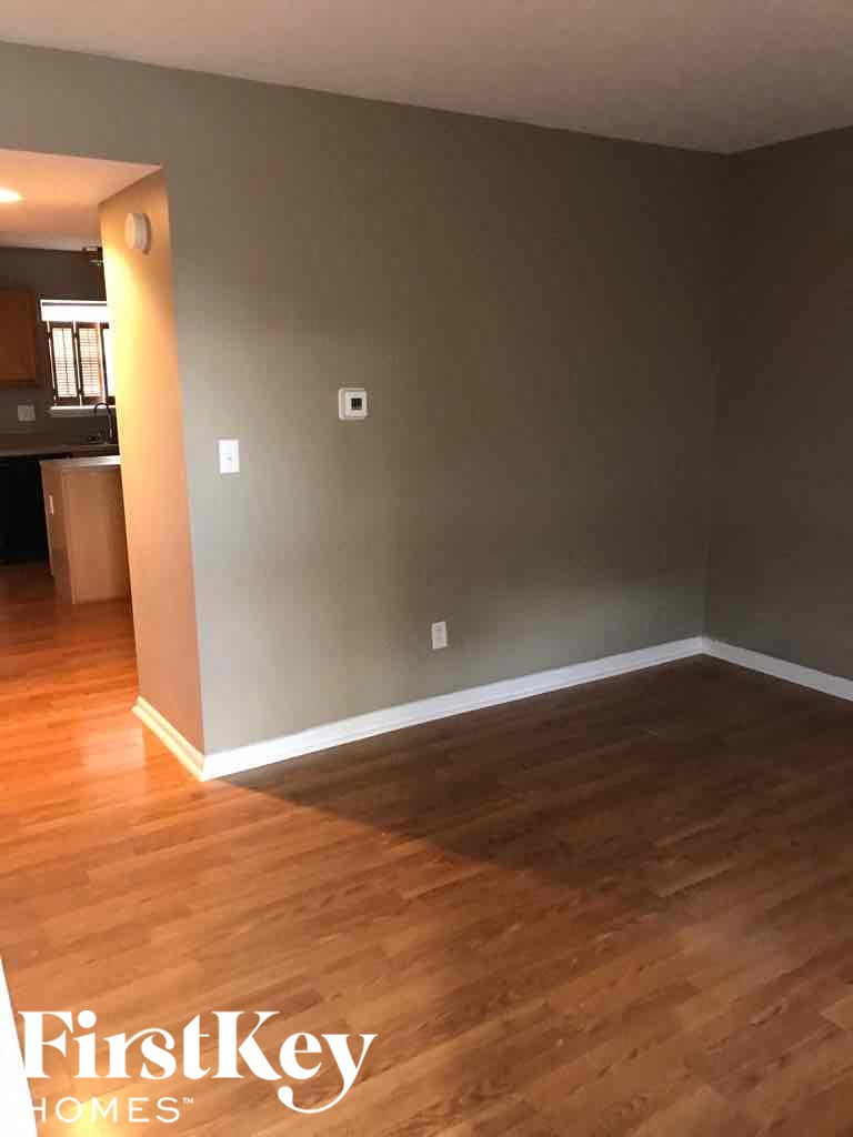 A room with wooden floors and a wall with a switch and a light switch.