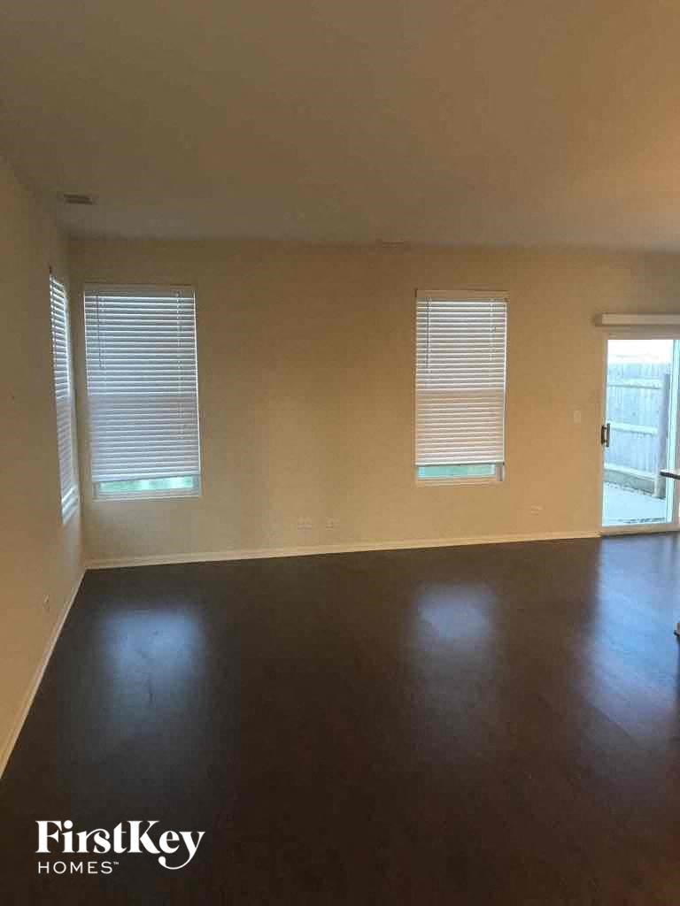 an empty living room with a hard wood floor and two windows