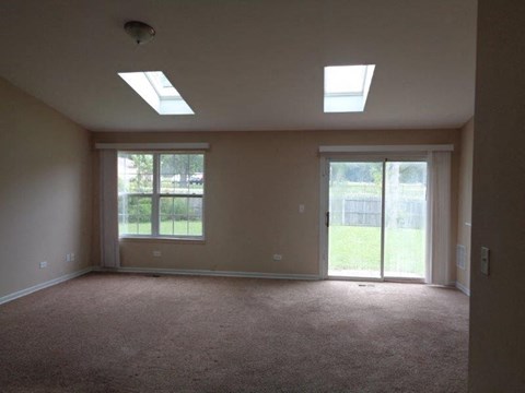 an empty living room with two windows and a door