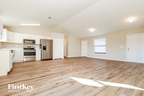 A spacious kitchen with wooden floors and white cabinets.