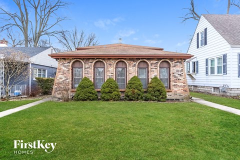 a small brick home with a gazebo on the front yard