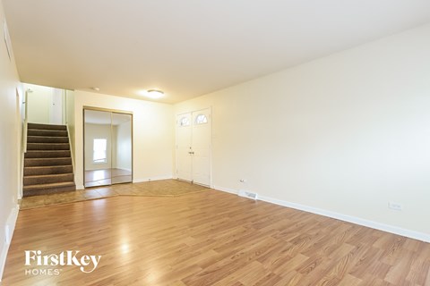 a living room with wood floors and white walls and a staircase