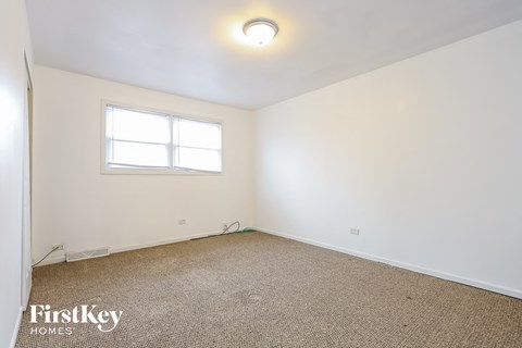 a bedroom with white walls and a window and a carpet