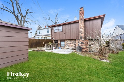 a backyard with a brick house and a yard with grass and a fence