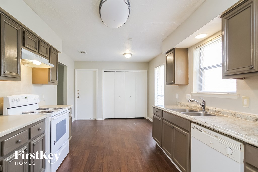 an empty kitchen with white appliances and wood flooring