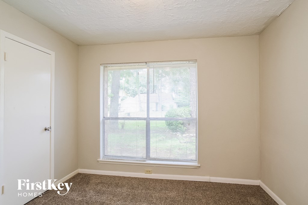 a bedroom with a large window and a carpeted floor