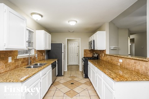 A kitchen with white cabinets and a granite countertop.