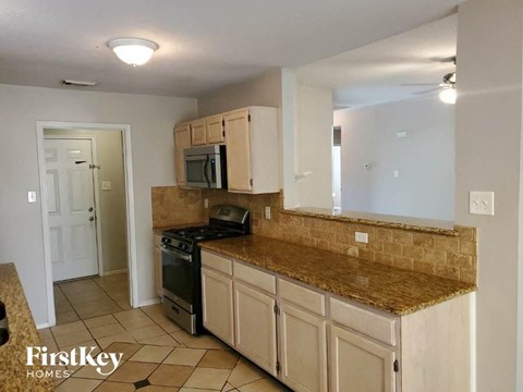 A kitchen with a brown counter top and white cabinets.