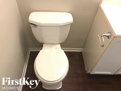 a white toilet in a small bathroom with a wood floor