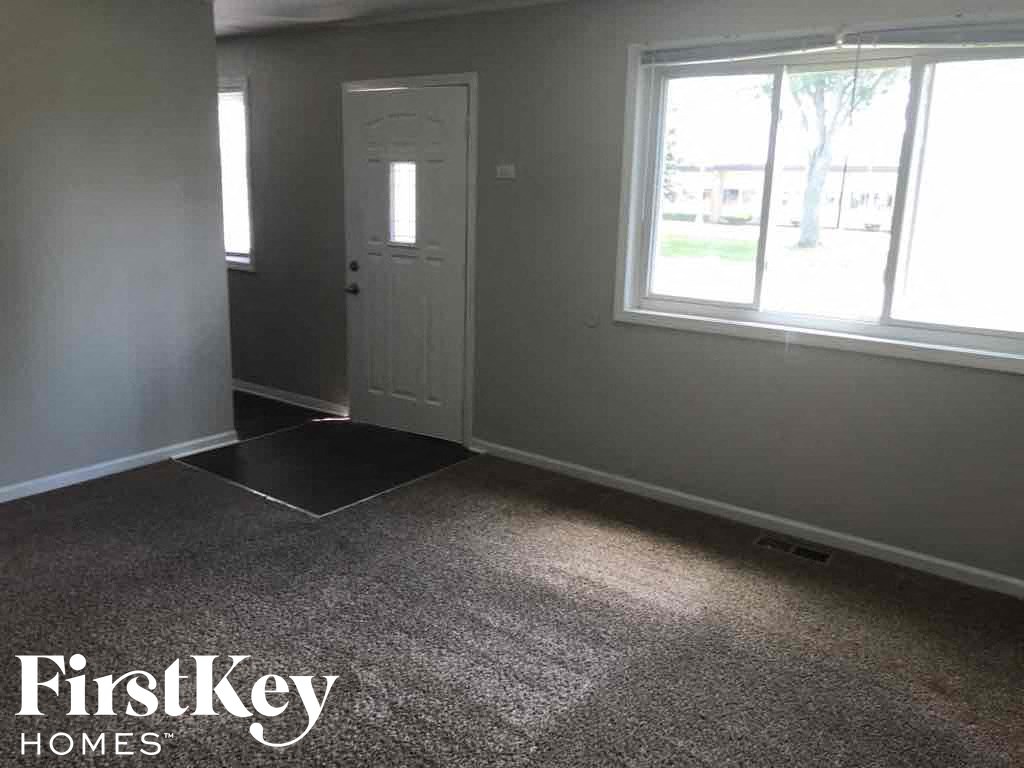a carpeted room with a white door and a window