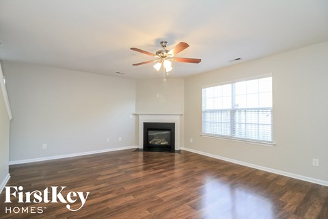 A spacious living room with a fireplace and a ceiling fan.