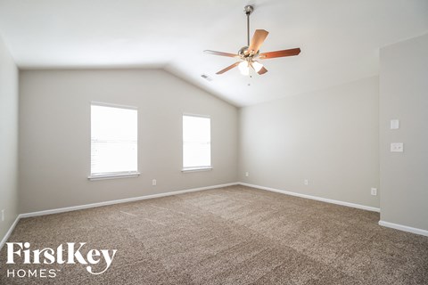 A spacious room with a carpeted floor and a ceiling fan.