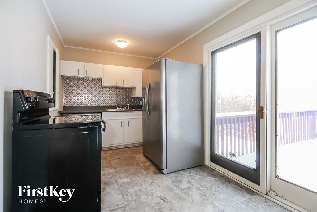 a kitchen with a refrigerator and a door to a balcony