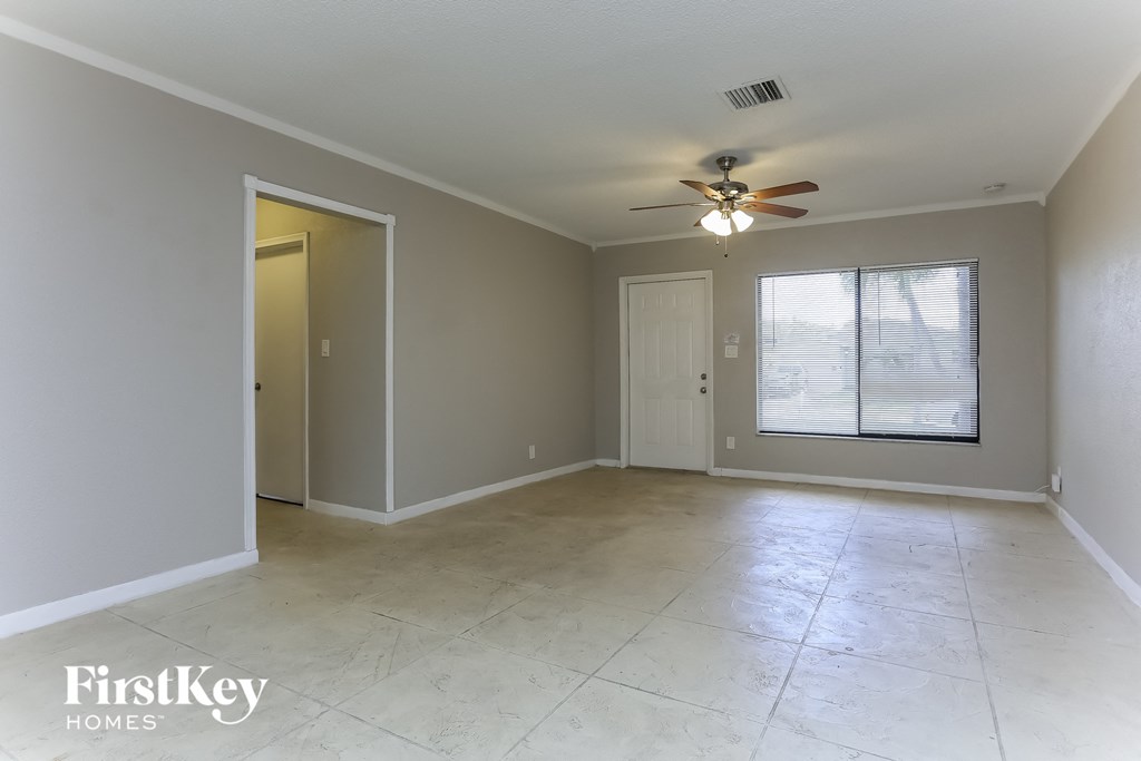 an empty living room with a ceiling fan and a window
