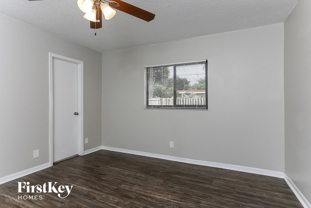 the living room of an empty house with a window and a ceiling fan