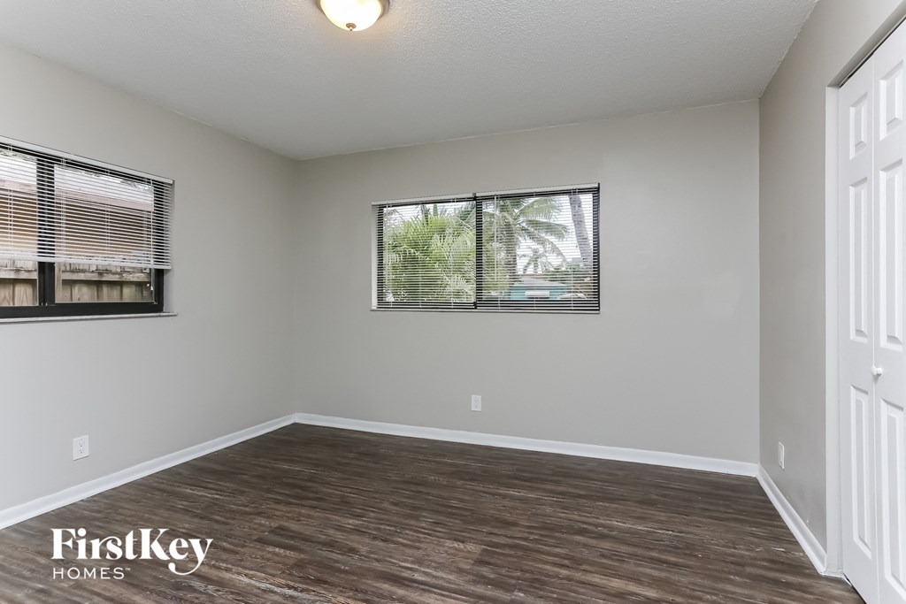 the living room of an empty house with wood flooring and two windows
